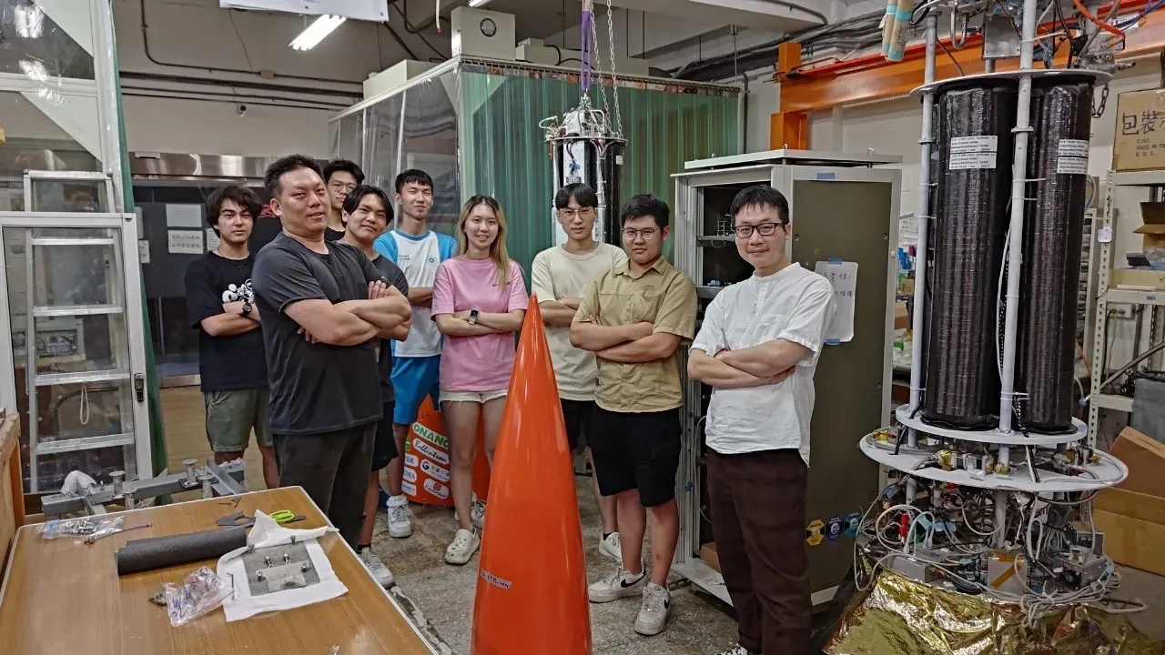 A group photo of everyone standing next to the rocket lab