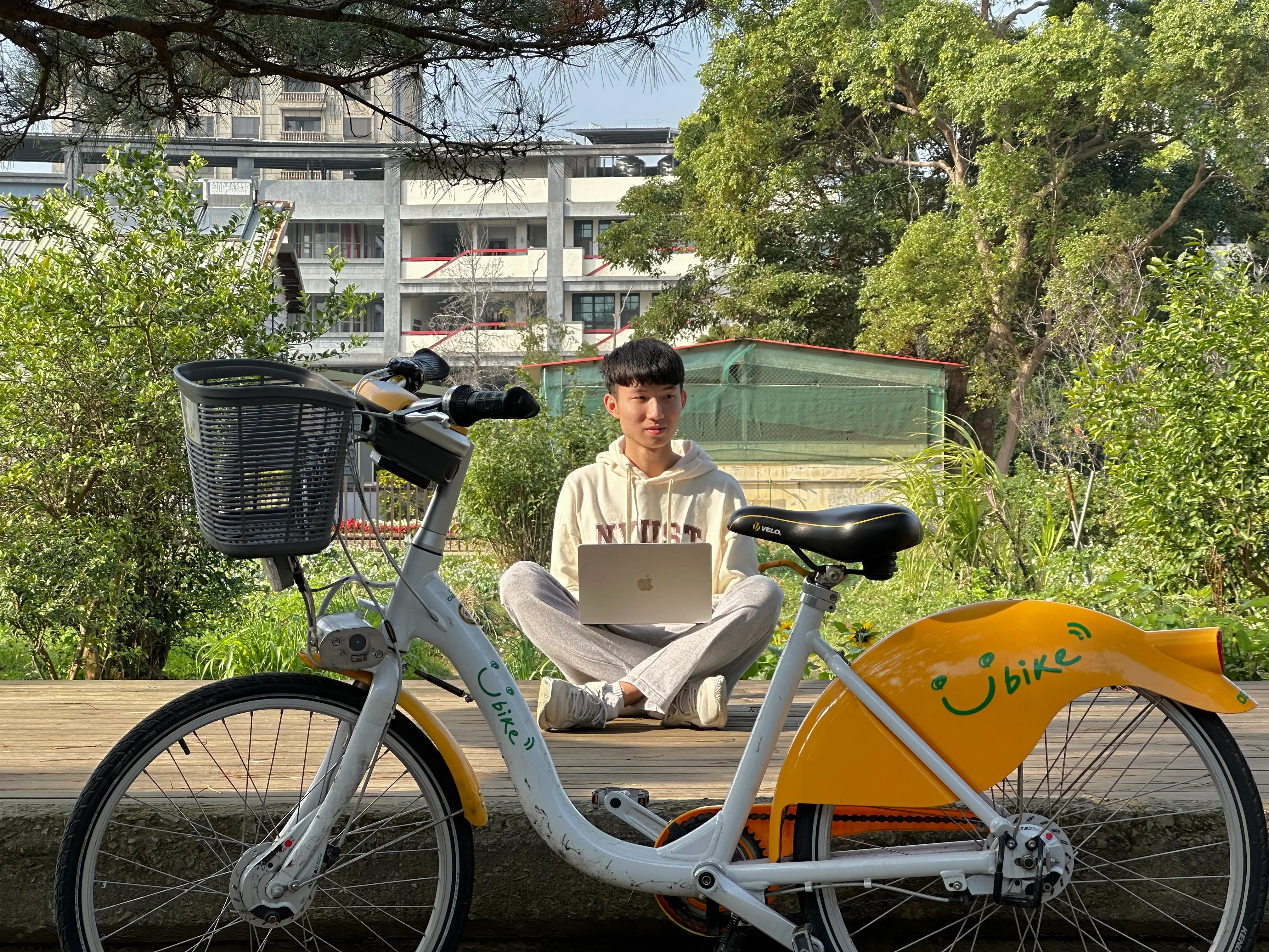 Sam sitting cross-legged behind a Ubike with a laptop
